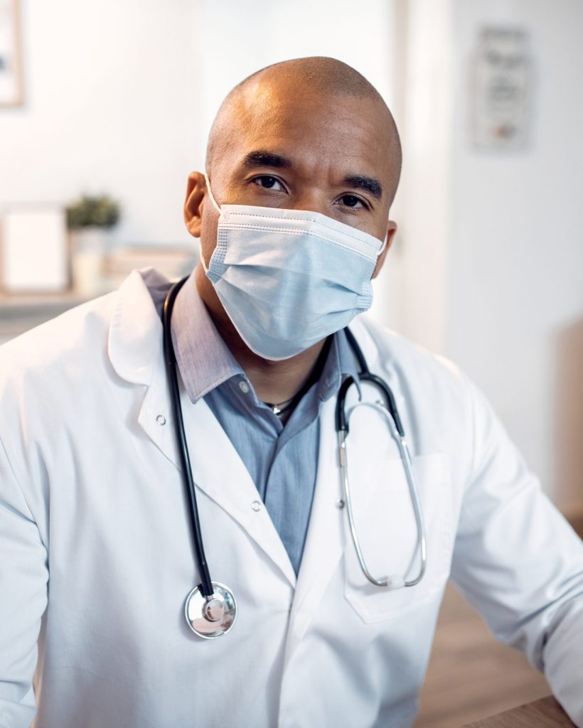Portrait of African American medical expert wearing protective face mask at doctor's office and looking at camera.